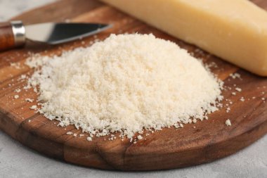 Arkaplanda lezzetli rendelenmiş parmesan peyniri olan ahşap tahta, yakın plan.