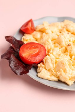 Lezzetli omlet, domatesli ve fesleğenli soluk pembe arka planda.