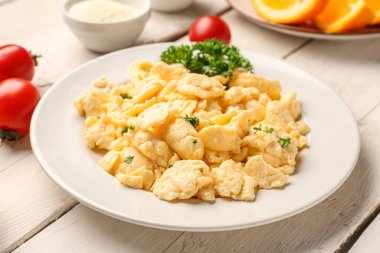 Beyaz ahşap arka planda malzemelerle çırpılmış yumurta tabağı.