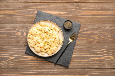 Kahverengi ahşap arka planda baharatlı omlet tabağı.