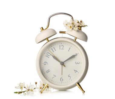 Blooming spring branches and alarm clock on white background