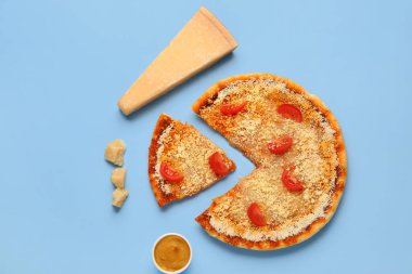Parmesan peynirli lezzetli pizza ve mavi arka planda domates.