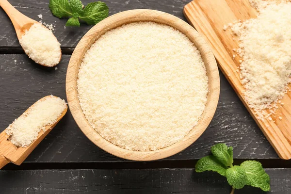 Koyu ahşap arka planda rendelenmiş parmesan peynirli kase, yakın plan.