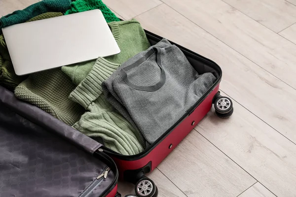 木製の床にラップトップとセーター付きのオープンスーツケース — ストック写真