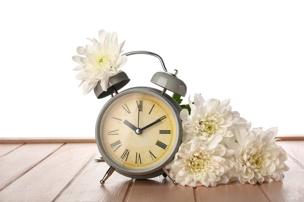 菊と目覚まし時計オンテーブルの上に白い背景 — ストック写真