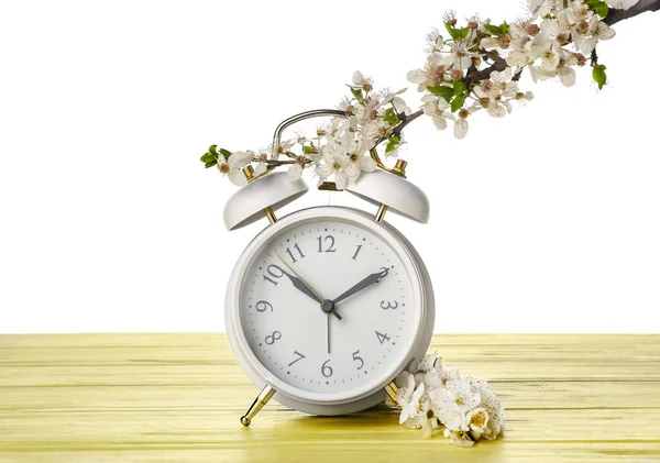 春の枝を開花し 白い背景を背景にテーブルの上に目覚まし時計 — ストック写真