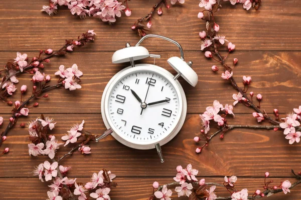 春の枝を開花し 木製のテーブルの上に目覚まし時計 — ストック写真