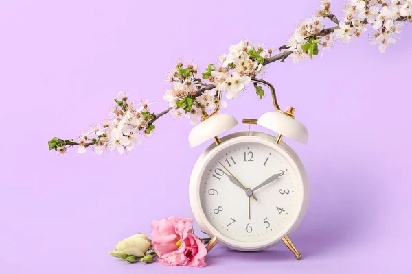 Blühende Frühlingszweige Mit Eustoma Und Wecker Auf Fliederfarbenem Hintergrund — Stockfoto