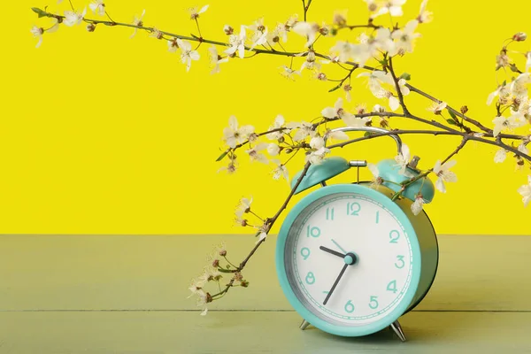 Квітучі Весняні Гілки Синій Будильник Зеленому Столі Біля Жовтої Стіни — стокове фото