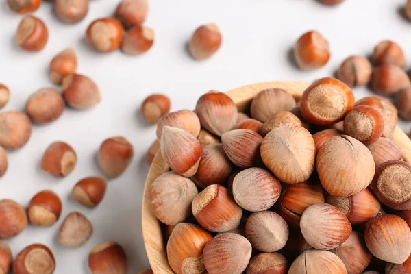 stock image Bowl with shelled hazelnuts on light background