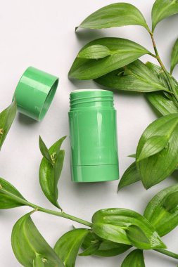 Deodorant şişesi ve beyaz arkaplanda yapraklar