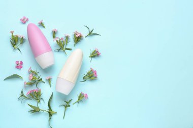 Mavi arka planda deodorant şişeleri ve çiçekler