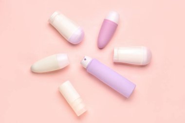 Pembe arka planda farklı deodorant şişeleri.