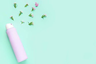 Deodorant şişesi ve mavi arka planda çiçekler.