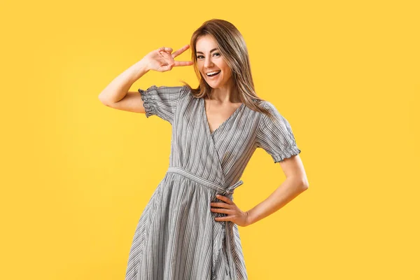 Beautiful Woman Striped Dress Showing Victory Gesture Yellow Background — Stock Photo, Image