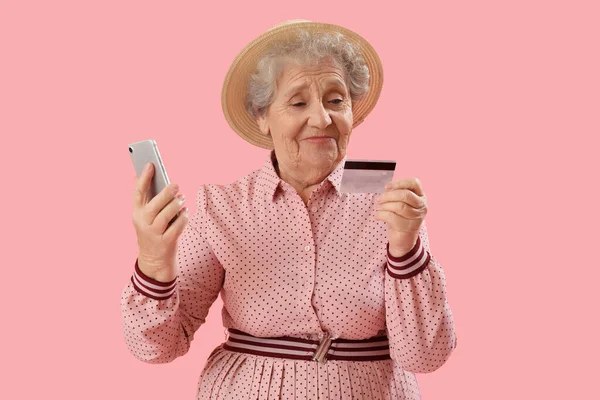 拥有粉色背景的手机和信用卡的老年妇女 — 图库照片