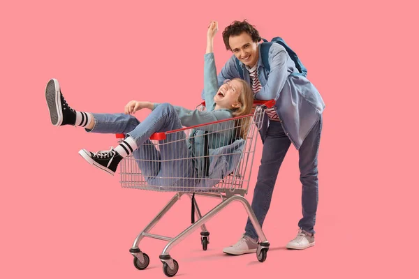 Tini Fiú Barátnőjével Bevásárlókocsiban Rózsaszín Háttér — Stock Fotó