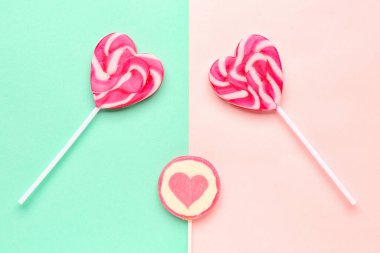 Turkuaz ve pembe arka planda kalp şeklinde lolipoplar.