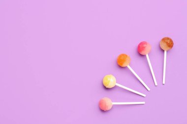 Mor arka planda tatlı lolipopları olan kompozisyon