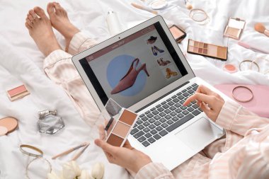 Dizüstü bilgisayarı olan ve palet heykeli yapan kadın beyaz battaniyeyle alışveriş yapıyor, yakın plan.