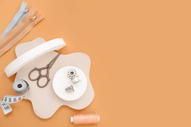 Turuncu arka planda terzi malzemesi olan podyumlar