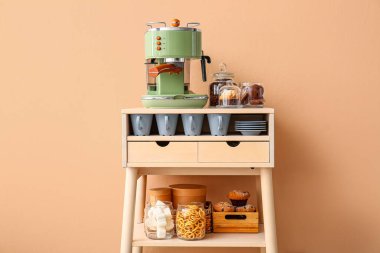 Kahve makineli masa, bej duvarın yanında aperatifler ve fincanlar
