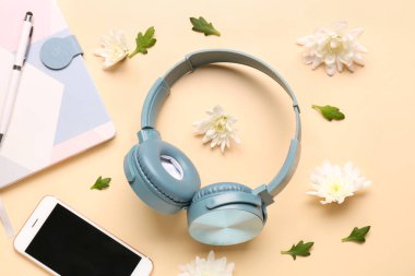 Renkli arka planda modern kulaklık, cep telefonu, defter ve çiçeklerle kompozisyon