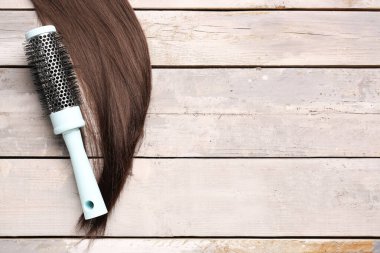 Açık ahşap arka planda yuvarlak fırçalı kahverengi saçlı