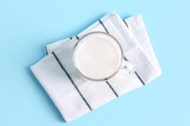 Mavi zemin üzerinde taze süt olan cam bardak.