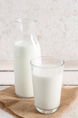 Hafif ahşap masada taze sütle şişe ve bardak.