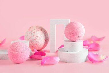Banyo bombalı podyumlar ve pembe arka planda çiçek yaprakları, yakın plan.