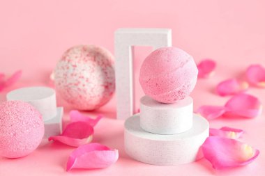 Banyo bombalı podyumlar ve pembe arka planda çiçek yaprakları, yakın plan.