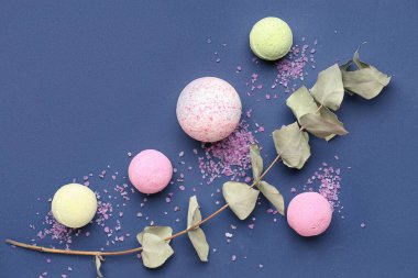 Mavi arka planda deniz tuzu ve okaliptüs dallı banyo bombaları.