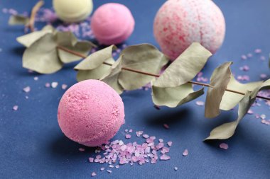 Mavi arka planda deniz tuzu ve okaliptüs dallı banyo bombaları, yakın plan.