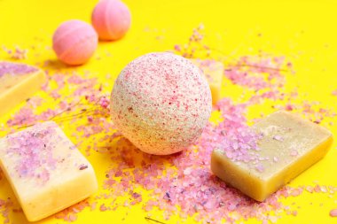 Sabunlu banyo bombaları, sarı arka planda deniz tuzu ve çiçekler, yakın plan.