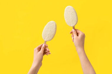 Sarı arka planda çikolata kaplı dondurma tutan kadın.