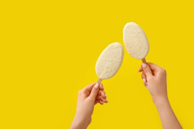 Sarı arka planda çikolata kaplı dondurma tutan kadın.