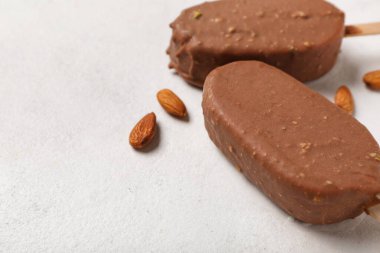 Lezzetli çikolata kaplı dondurma ve beyaz masada badem fıstığı.