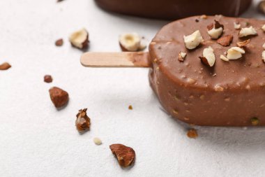 Lezzetli çikolata kaplı dondurma, beyaz masada ezilmiş fındıklar, yakın plan.