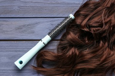 Kıvırcık kahverengi saçlı, mor ahşap arka planda yuvarlak fırçalı.