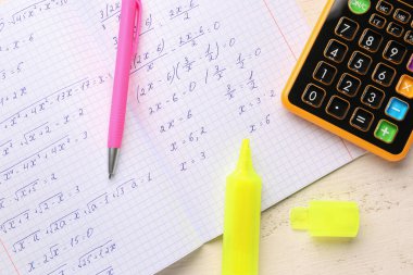 Matematik formülleri, hesap makineleri ve beyaz ahşap masa üzerindeki kalemler ile metin kitabı