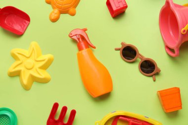 Yeşil arka planda plaj aksesuarları olan bebek için güneş kremi