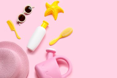 Pembe arka planda plaj aksesuarları olan bebek için güneş kremi.