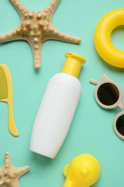 Plaj aksesuarları ve yeşil arka planda deniz yıldızları olan bebek için güneş kremi.