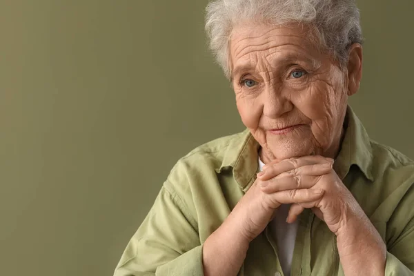 Thinking senior woman on green background, closeup