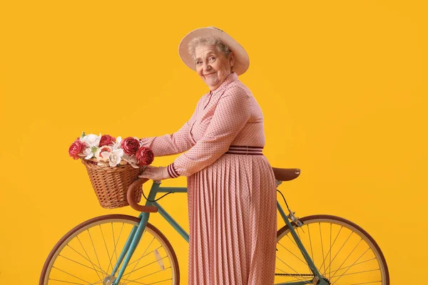 Старшая Женщина Велосипедом Корзиной Цветов Желтом Фоне — стоковое фото