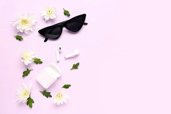 Composition with modern earphones, case, sunglasses and chrysanthemum flowers on color background