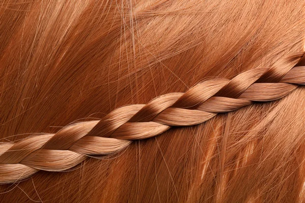 Ginger hair with pigtail as background, closeup