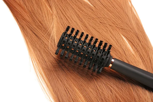 Ginger hair with round brush on white background, closeup