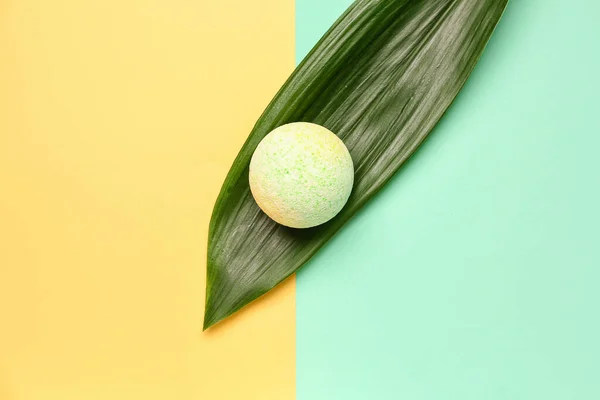 Bath bomb with palm leaf on color background